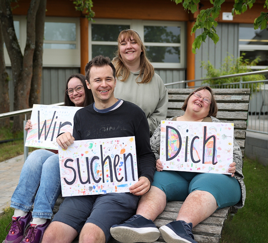 Menschen halten Schilder hoch "Wir suchen Dich"