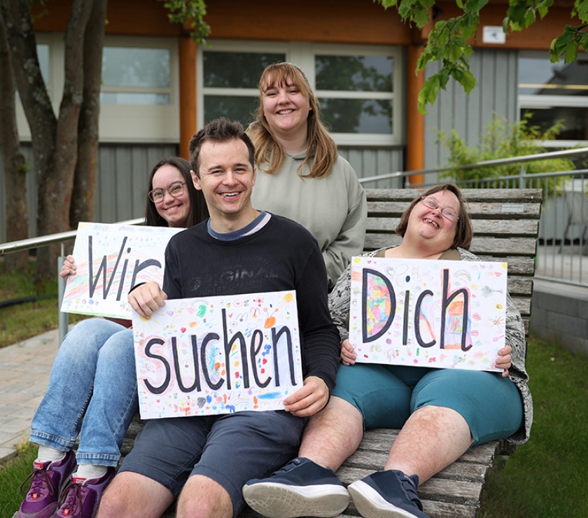 Menschen halten Schilder hoch "Wir suchen Dich"